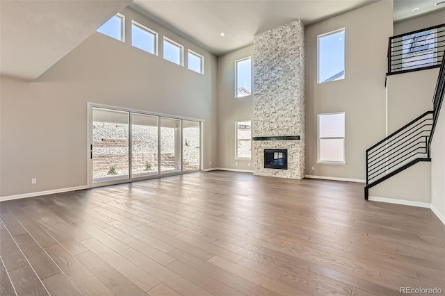 4748 Weitbrec Ln, Castle Rock, CO 80104 - unfurnished living room with a towering ceiling, baseboards, stairway, wood finished floors, and a stone fireplace