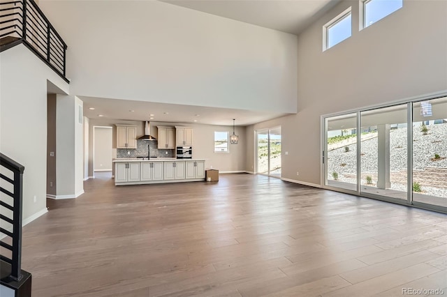 4748 Weitbrec Ln, Castle Rock, CO 80104 - unfurnished living room with a sink, a towering ceiling, baseboards, wood finished floors, and stairs