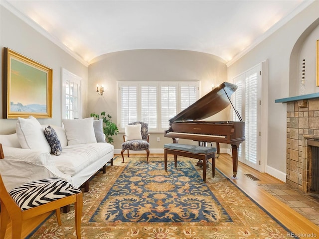 living room with ornamental molding, wood-type flooring, vaulted ceiling, and a fireplace