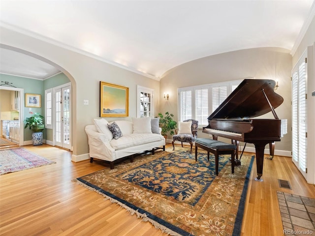 living room with ornamental molding, lofted ceiling, plenty of natural light, and hardwood / wood-style floors