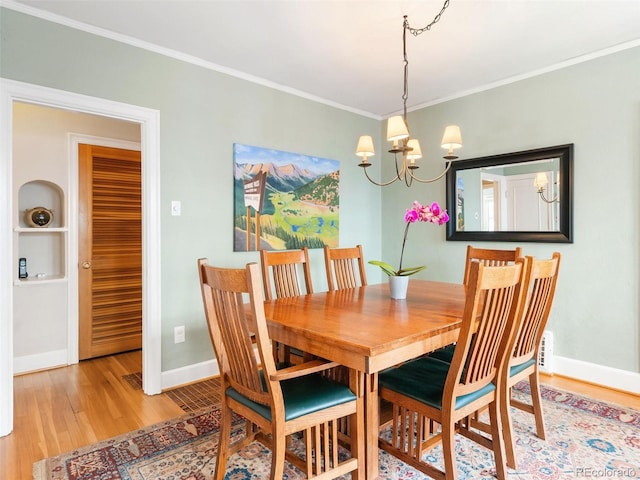 dining room with light hardwood / wood-style flooring, a notable chandelier, and ornamental molding