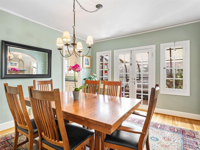 dining room with french doors, ornamental molding, a chandelier, and hardwood / wood-style floors