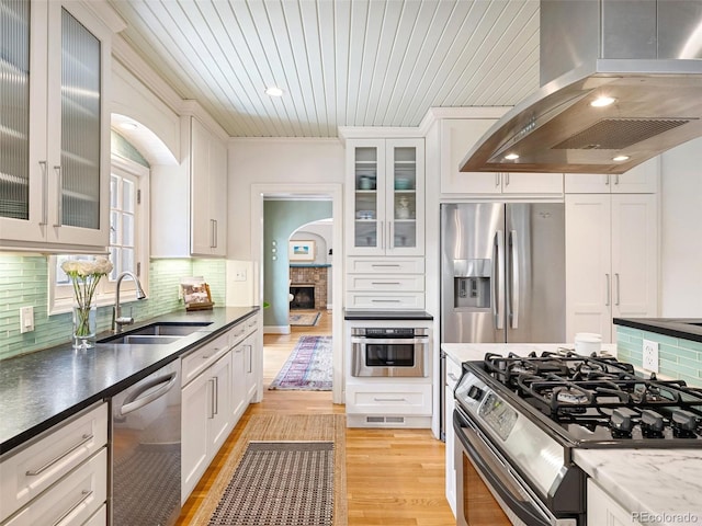 kitchen with appliances with stainless steel finishes, island range hood, sink, and white cabinets