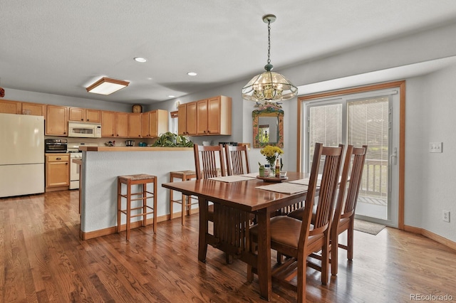 dining space with wood finished floors, a chandelier, baseboards, and recessed lighting