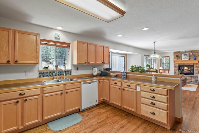 kitchen with white dishwasher, a sink, a peninsula, light brown cabinets, and recessed lighting