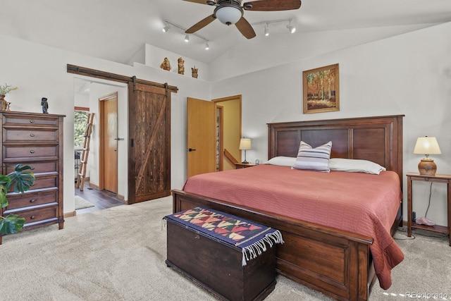 carpeted bedroom with track lighting, lofted ceiling, a barn door, and a ceiling fan
