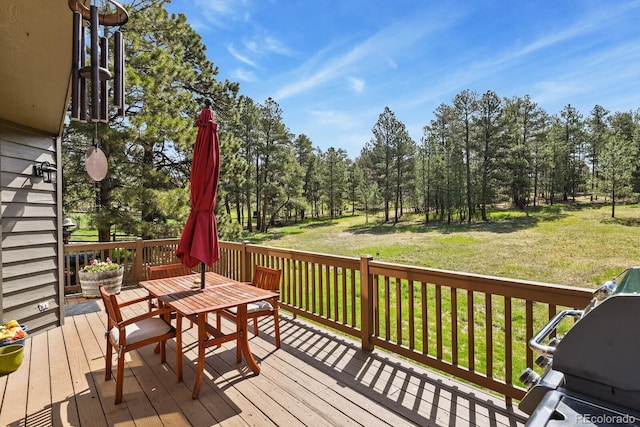 wooden terrace with outdoor dining area and a yard
