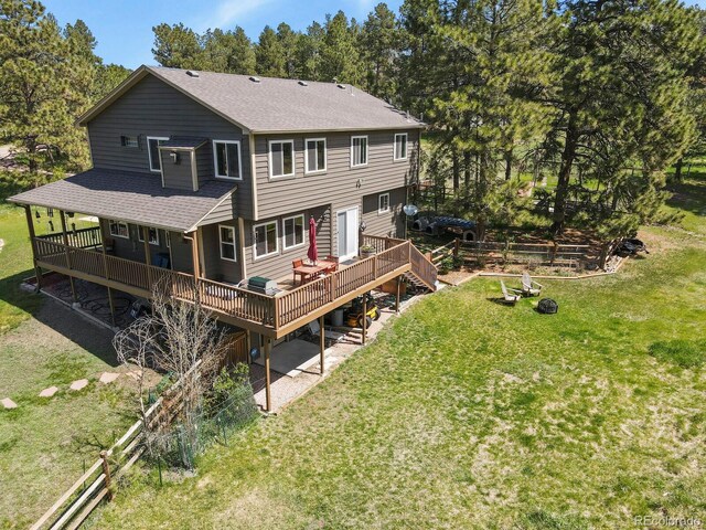 rear view of house with a deck, a shingled roof, and view of wooded area