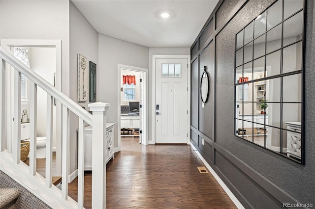 entrance foyer featuring dark wood-type flooring, stairway, visible vents, and baseboards