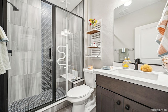 bathroom with toilet, a stall shower, a textured wall, and vanity