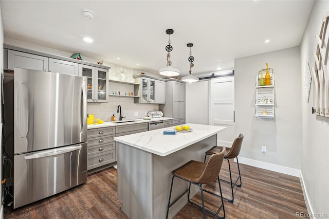 kitchen with a barn door, gray cabinetry, a sink, and freestanding refrigerator