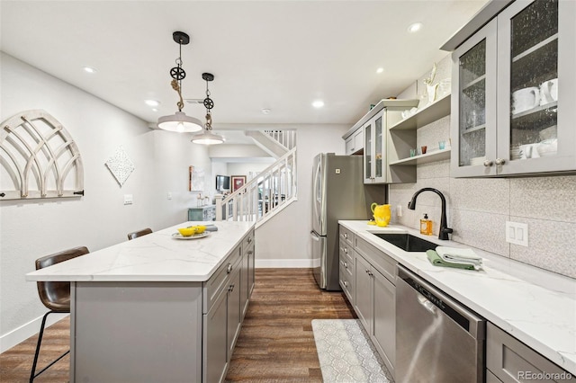 kitchen with tasteful backsplash, gray cabinets, appliances with stainless steel finishes, a sink, and a kitchen island