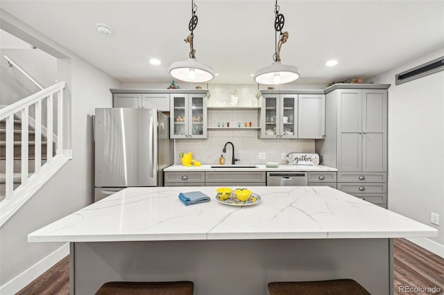 kitchen featuring a kitchen breakfast bar, tasteful backsplash, appliances with stainless steel finishes, and gray cabinetry