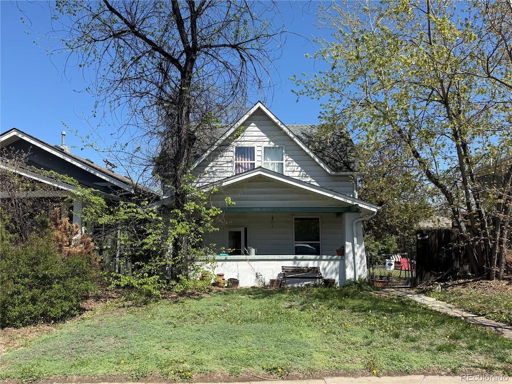 view of front of home with fence, covered porch, and a front lawn