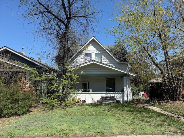 view of front of home with fence, covered porch, and a front lawn