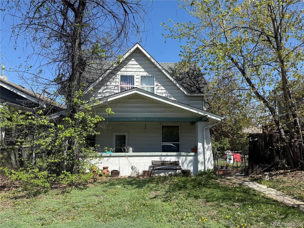 view of front facade featuring fence, covered porch, and a front yard