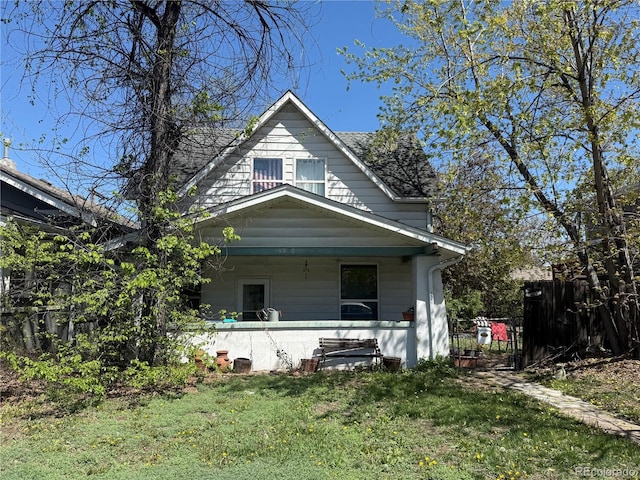view of front facade featuring fence, covered porch, and a front yard