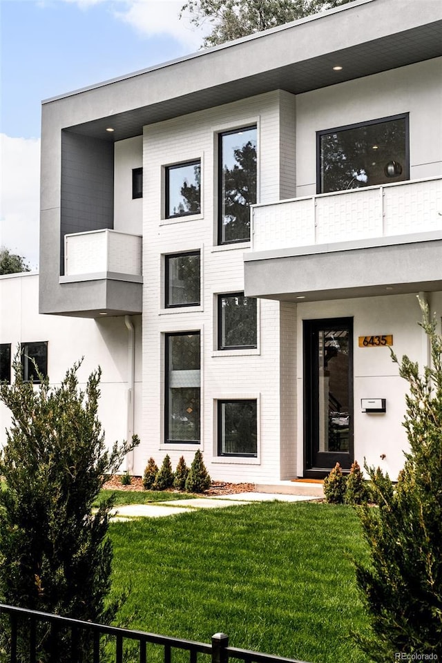 view of front facade with a balcony and a front yard