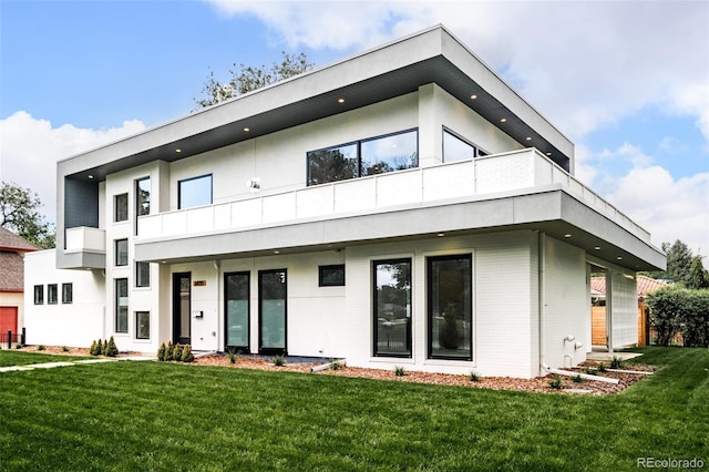 rear view of house with a yard and a balcony