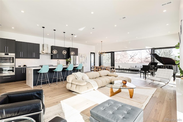 living room featuring light hardwood / wood-style flooring, a wealth of natural light, and a notable chandelier