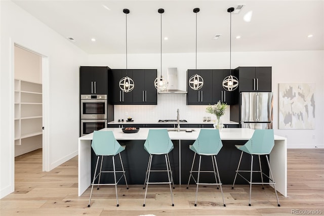 kitchen with a breakfast bar area, decorative light fixtures, and appliances with stainless steel finishes