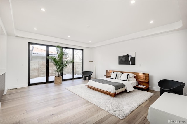 bedroom with a raised ceiling, access to exterior, and light hardwood / wood-style floors