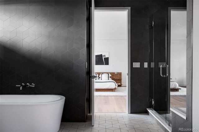 bathroom featuring tile patterned flooring, plus walk in shower, and tile walls