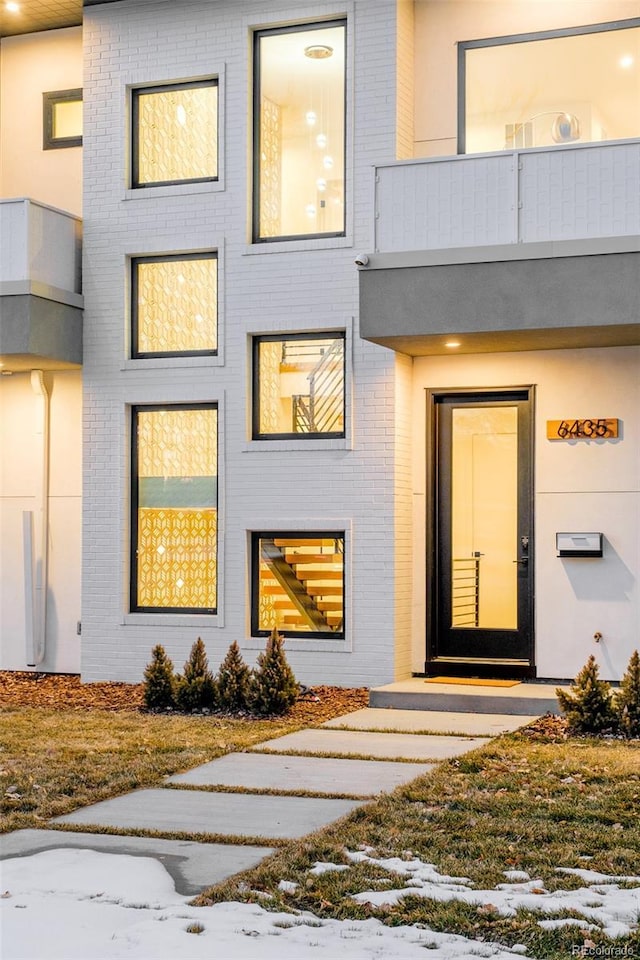 snow covered property entrance featuring a balcony