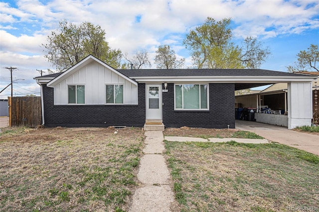 2514 E Bijou St, Colorado Springs, CO 80909 - view of front facade featuring board and batten siding, a carport, brick siding, and concrete driveway