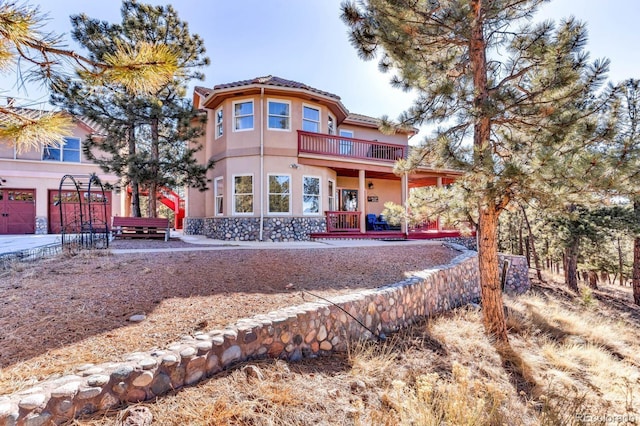31 Black Fawn Ln, Westcliffe, CO 81252 - rear view of house featuring a balcony, a tiled roof, stucco siding, and stone siding