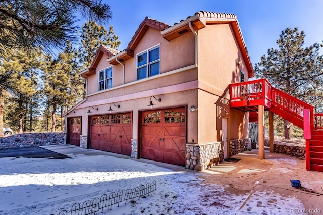 31 Black Fawn Ln, Westcliffe, CO 81252 - view of front of home with stone siding, a tiled roof, an attached garage, stairs, and stucco siding