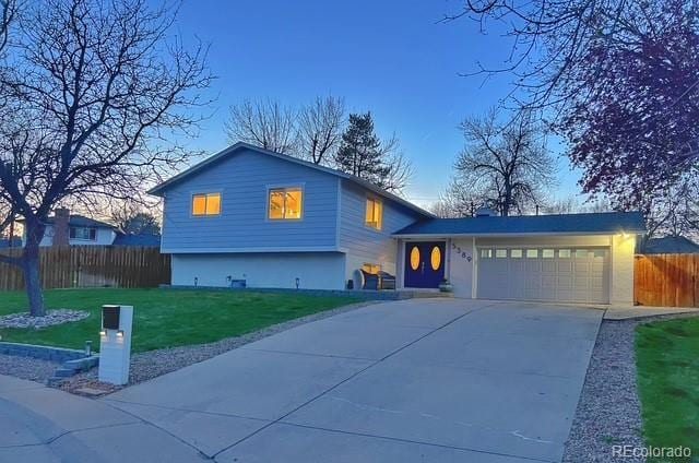 split level home featuring a yard, driveway, an attached garage, and fence