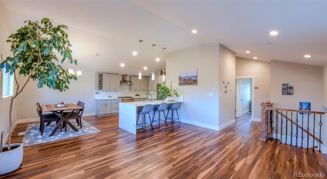 kitchen with light countertops, wall chimney exhaust hood, lofted ceiling, and a breakfast bar