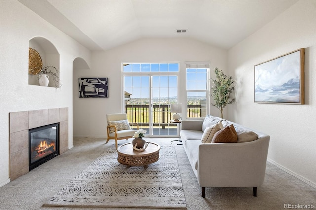 carpeted living room featuring a tile fireplace and vaulted ceiling