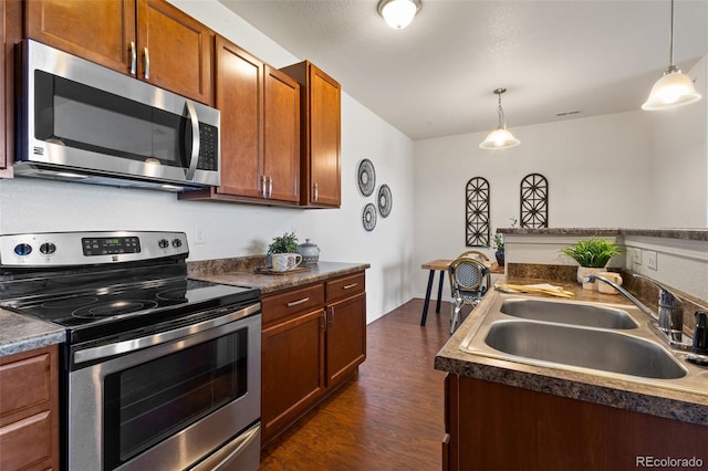 kitchen featuring dark hardwood / wood-style flooring, sink, stainless steel appliances, and hanging light fixtures