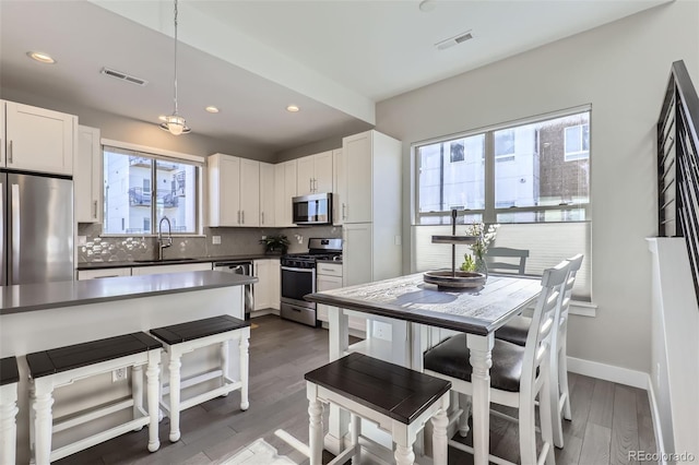 kitchen with pendant lighting, sink, stainless steel appliances, and white cabinets