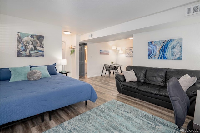 bedroom with visible vents, baseboards, and wood finished floors