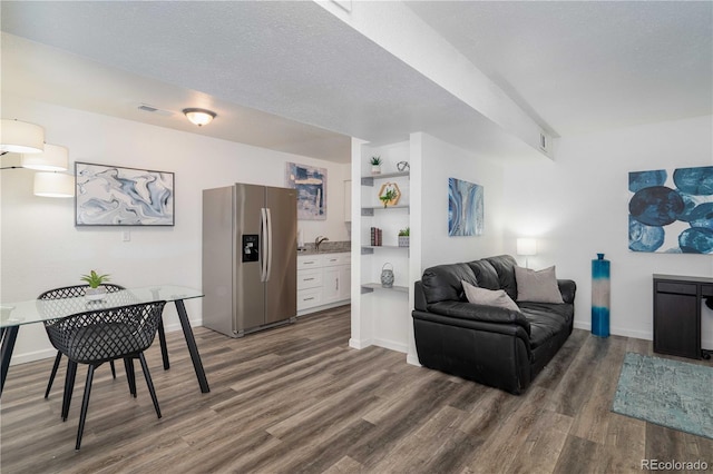 living room with a textured ceiling, dark wood finished floors, visible vents, and baseboards