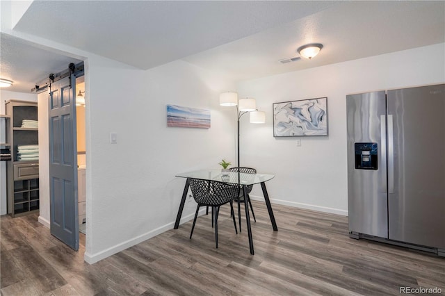 dining area with a barn door, visible vents, and wood finished floors