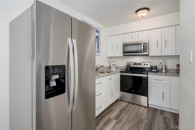 kitchen featuring appliances with stainless steel finishes, white cabinets, a sink, and dark wood-style floors