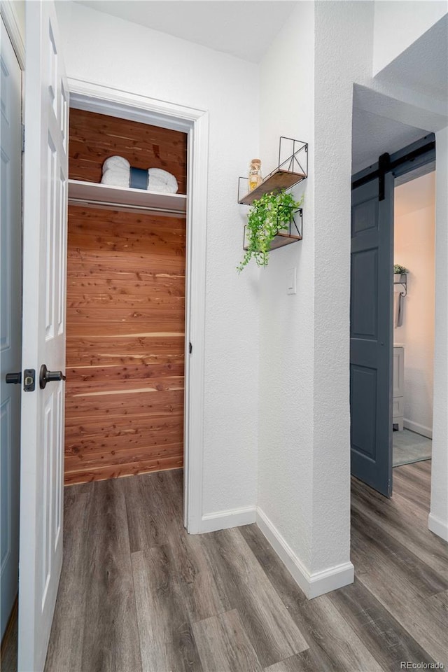 interior space featuring a barn door, wood finished floors, and baseboards