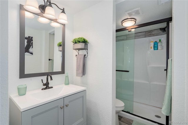 bathroom with toilet, a shower stall, visible vents, and vanity