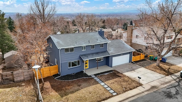 traditional home with driveway, a shingled roof, a chimney, an attached garage, and fence