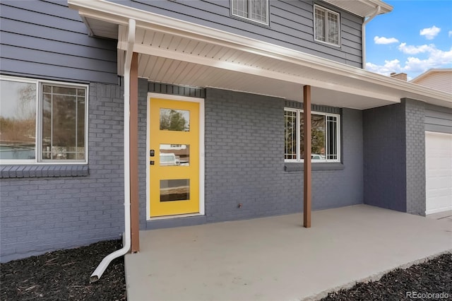 doorway to property featuring brick siding and a garage