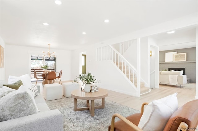 living area featuring recessed lighting, a fireplace, stairs, light wood-style floors, and a chandelier