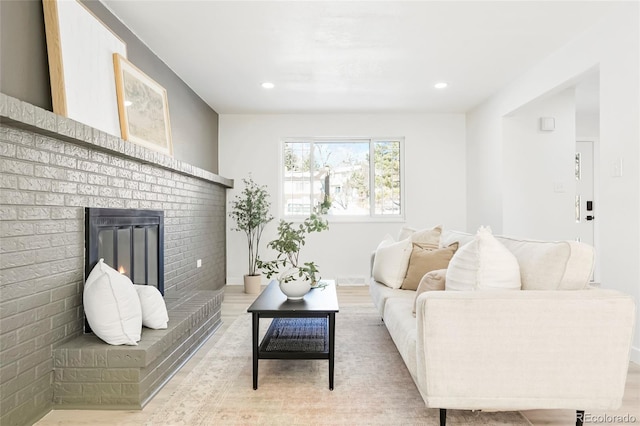 living room featuring a brick fireplace, recessed lighting, light wood-type flooring, and baseboards