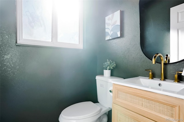 bathroom featuring toilet, vanity, and a textured wall