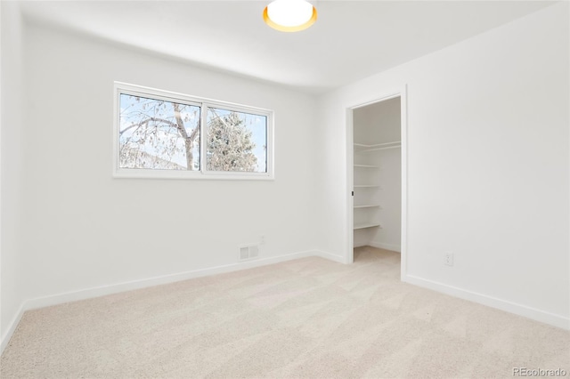 unfurnished bedroom featuring visible vents, a closet, carpet, baseboards, and a spacious closet