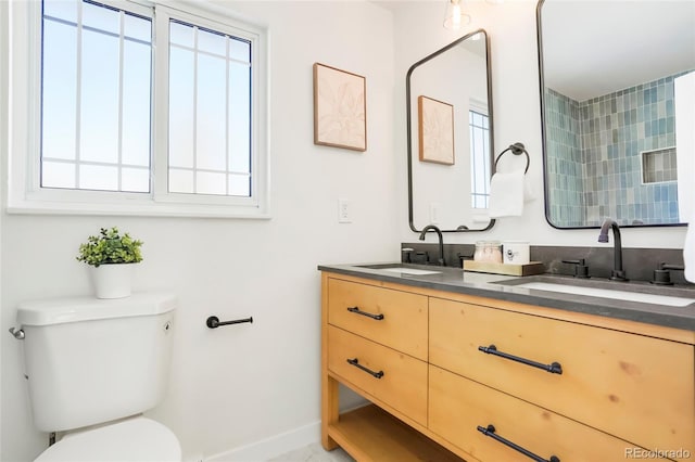 full bathroom featuring double vanity, toilet, baseboards, and a sink