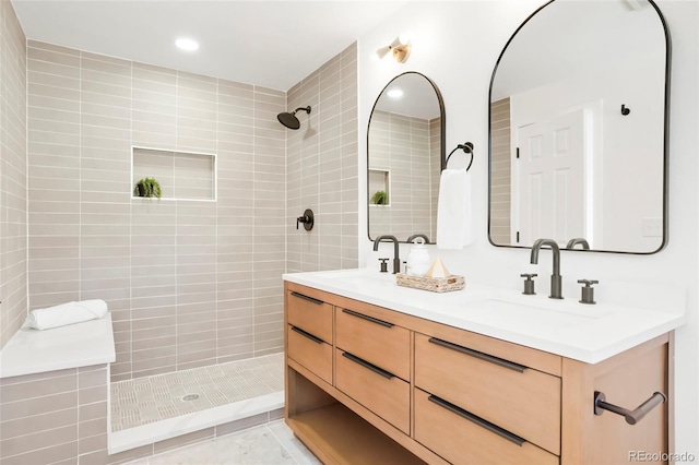 bathroom featuring double vanity, tile patterned floors, a tile shower, and a sink